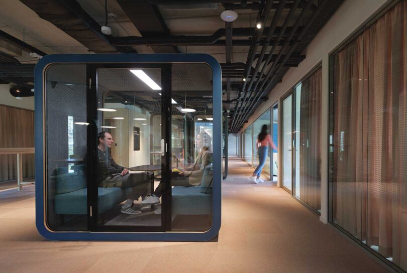 view in modern office space with man working in an enclosed office pod