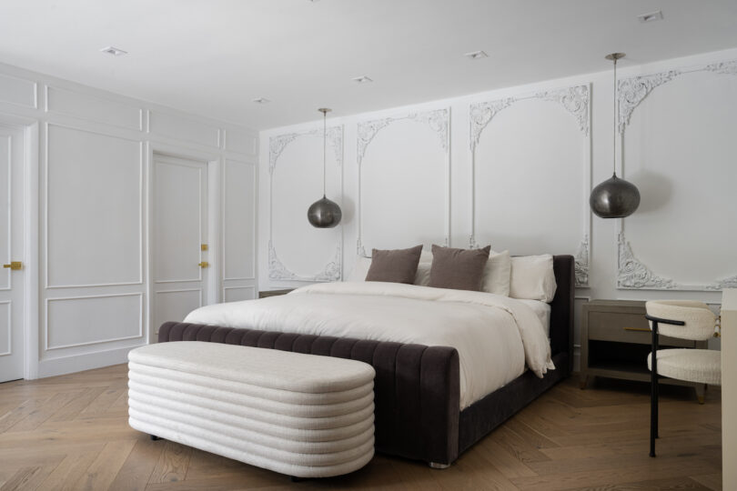 The master bedroom with adorned wall trim and pendant lights