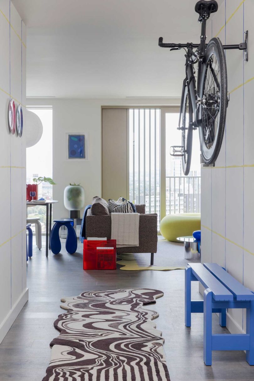 view down apartment hallway with blue bench and hanging bike looking into open living room and dining room