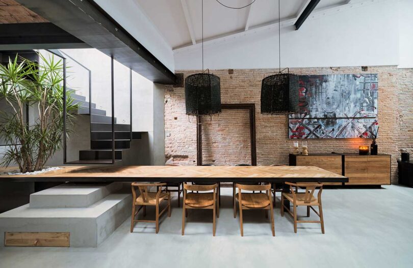 interior shot of modern dining room with long wood table that stretches to become part of unique staircase