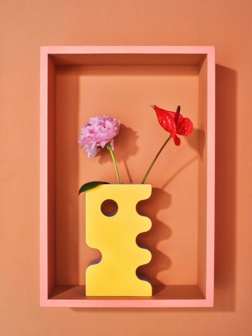 framed box holding a yellow abstract vase on peach wall