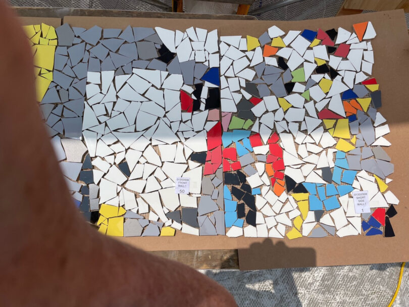 detail of large colorful curved mosaic wall art installation being constructed