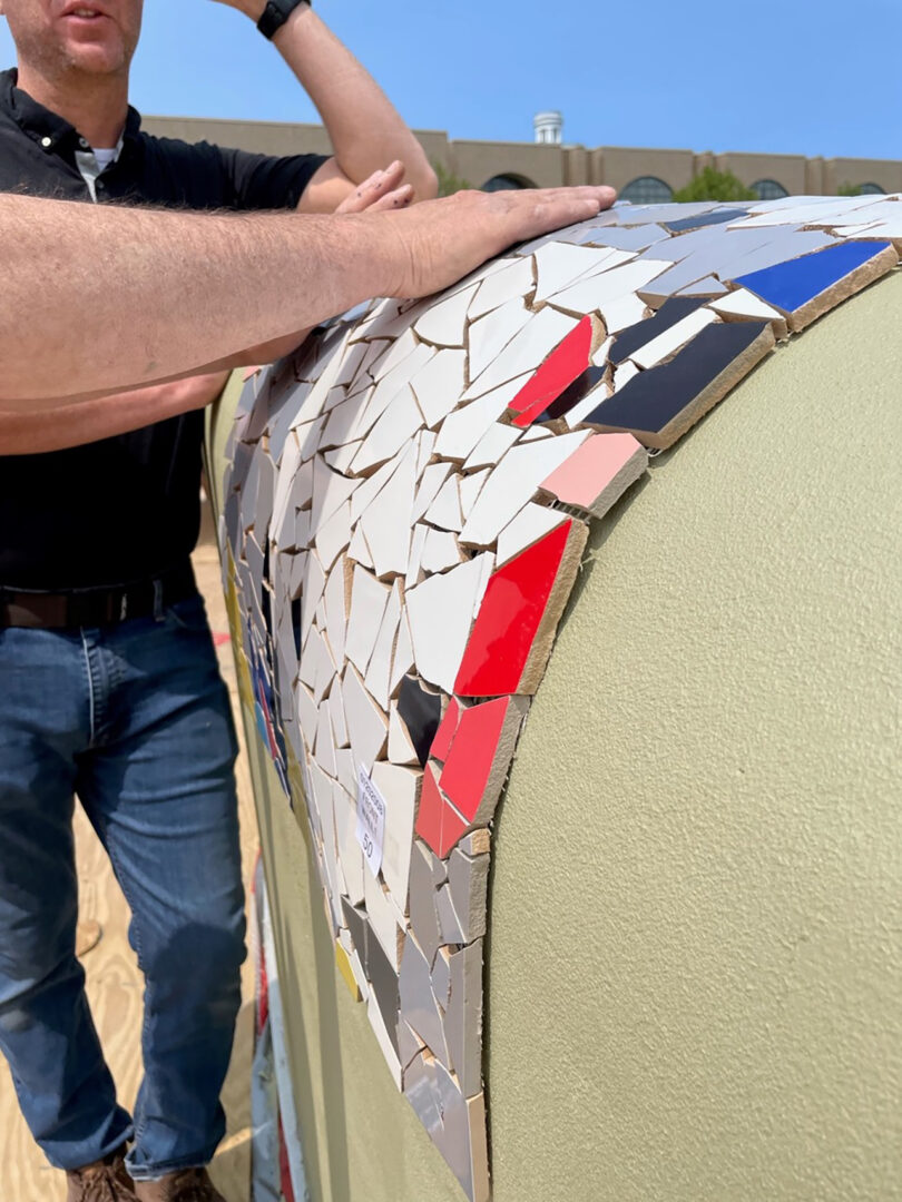 detail of large colorful curved mosaic wall art installation being constructed