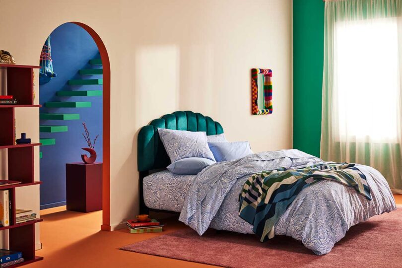 angled view of modern bedroom with green upholstered headboard and colorful bedding