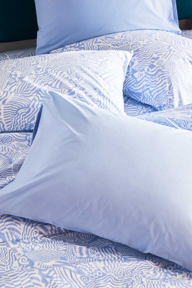 layered view of modern light blue and white patterned bedding with light blue pillows