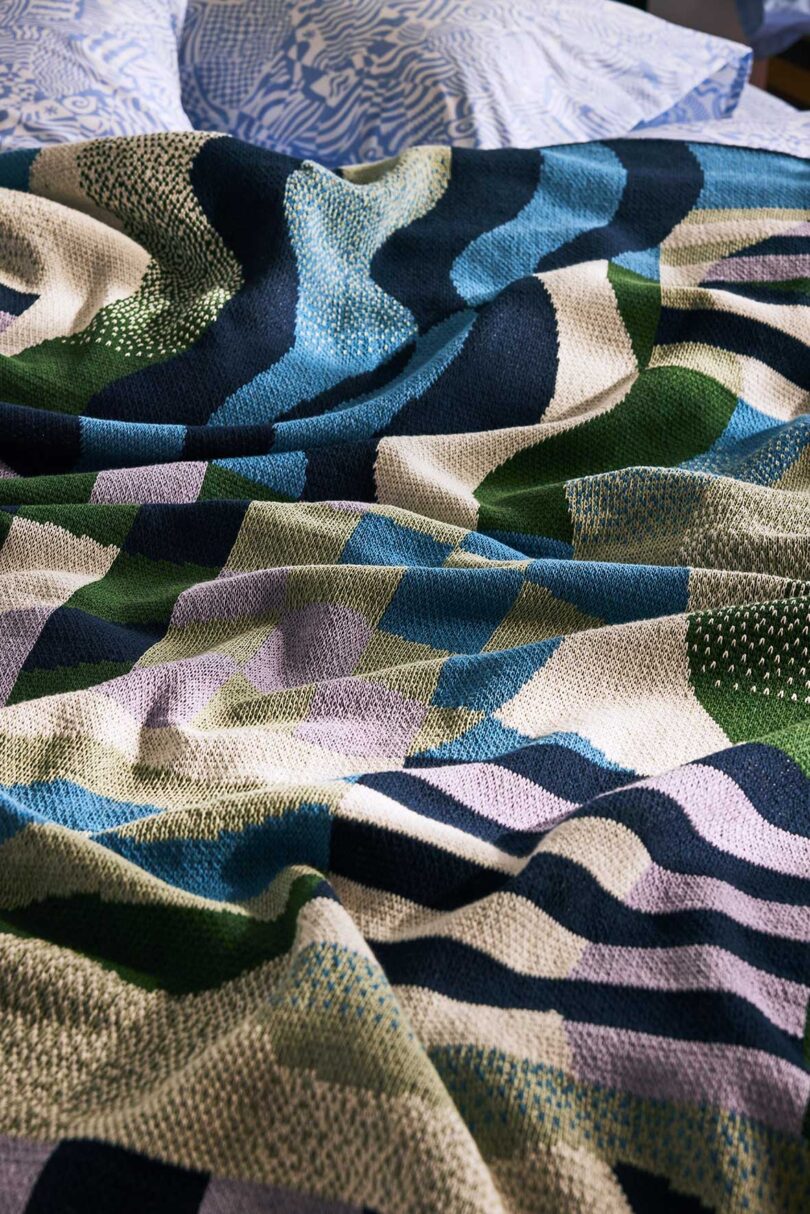 messy patterned blanket in many colors laying on bed