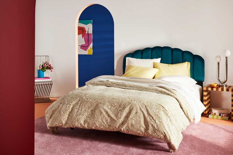 angled view of modern bedroom with green upholstered headboard and colorful bedding