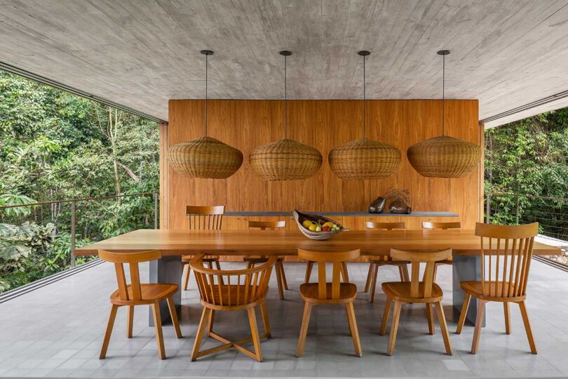 Vista interior del moderno comedor con mesa y sillas de madera y parte de la pared de madera detrás
