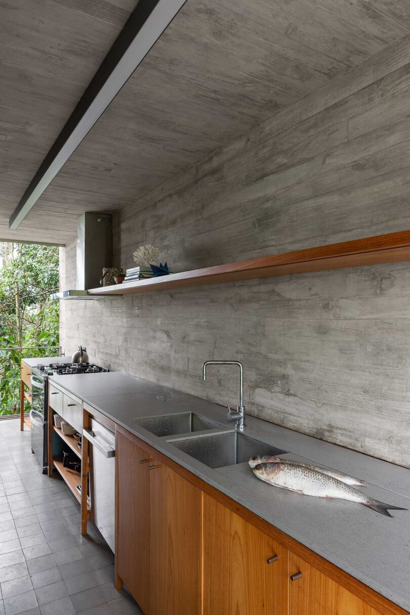 Vista en ángulo de la moderna cocina minimalista con paredes de hormigón y armarios inferiores de madera.