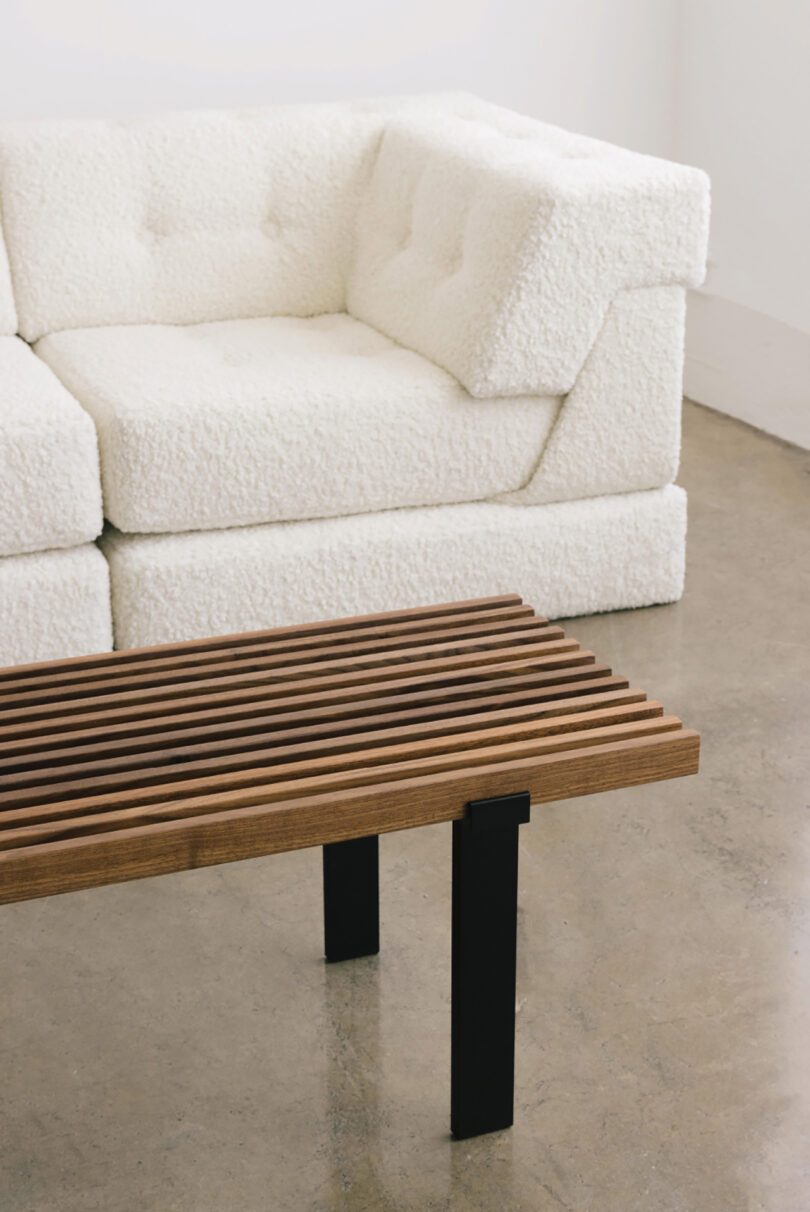 corner of white modular sofa and slatted wood coffee table