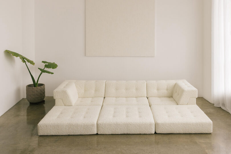 three-seater single layer white sofa with extended cushions in a styled interior space