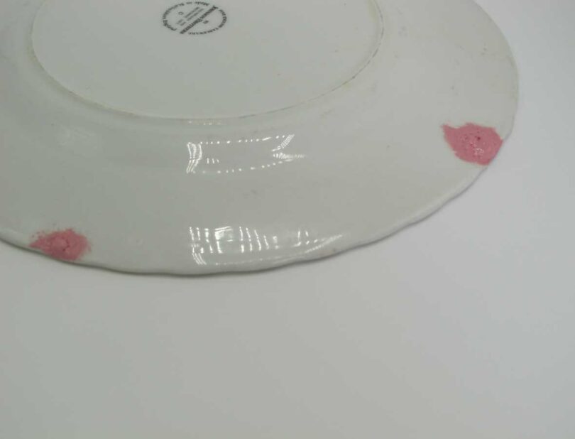 closeup of backside of white plate with pink repairs