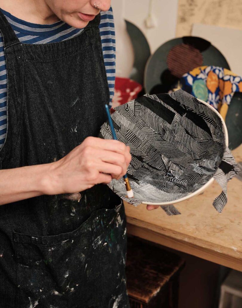 person in black apron holding a black and white plate with repairs