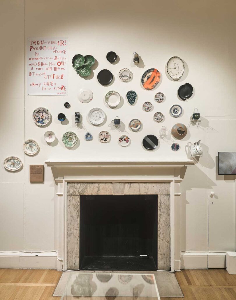 view of fireplace on white wall with collage of various plates that have been repaired