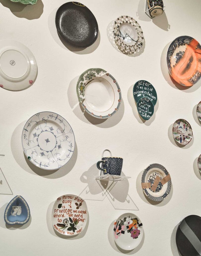 closeup of white wall with lots of various types of plates hanging