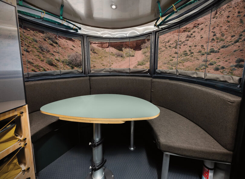 Interior of REI Airstream trailer front with seating and table accessible for dining.