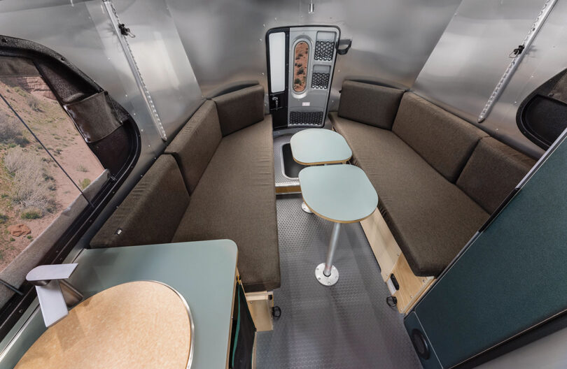 Interior of REI Airstream trailer rear area configured into large length of seating with two small tables inbetween.