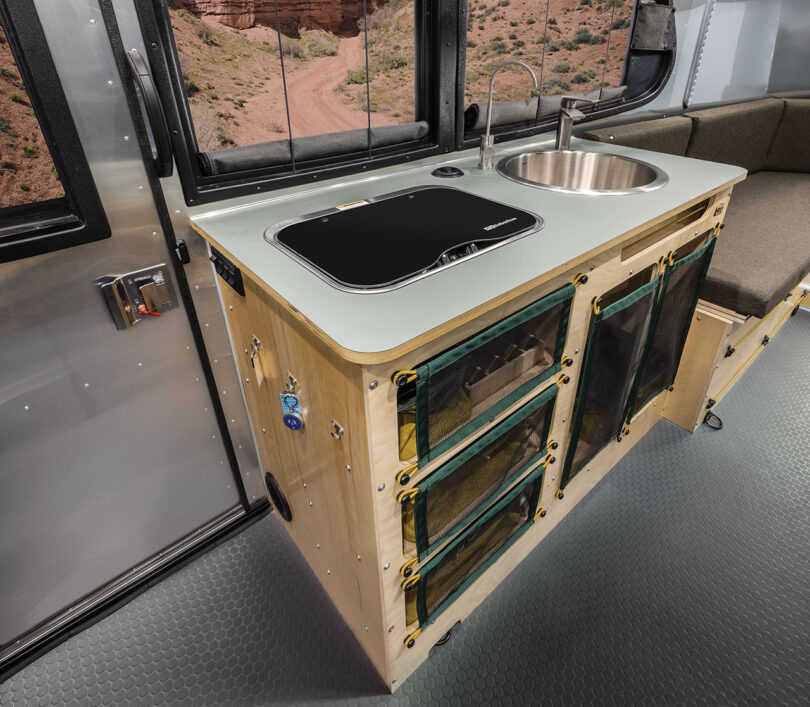 Angled view of the multi-layered green slate countertop, adorned with exposed birch plywood within the REI Edition Airstream, with burners covered.