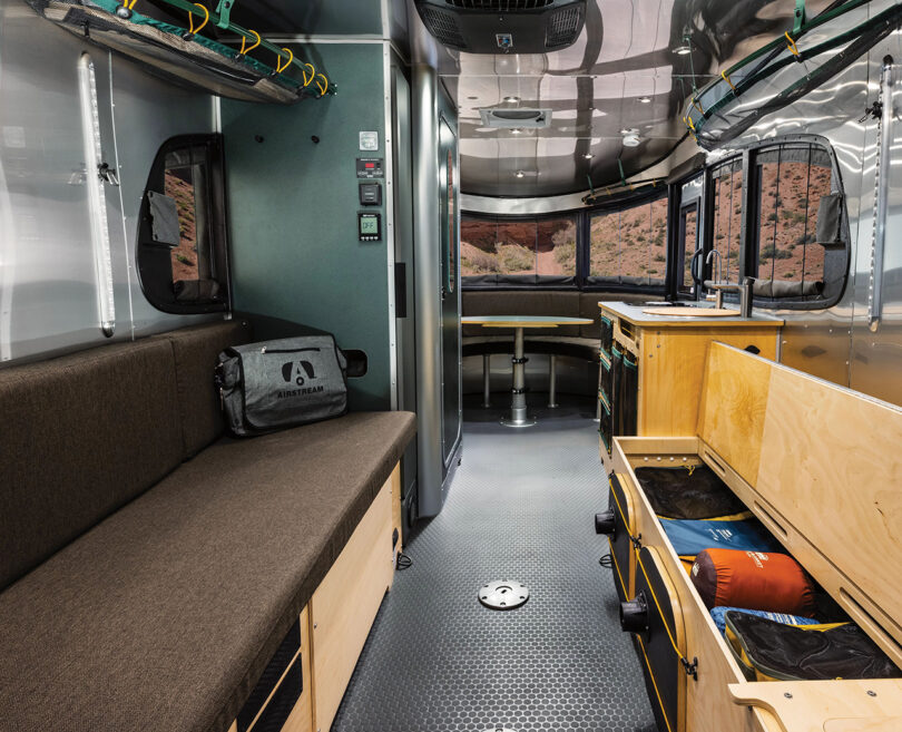 Storage options area in the rear seating and sleep quarters of the REI edition Airstream trailer, filled with camping and adventuring gear.