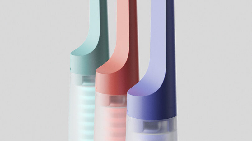 Close up the where the toothbrush neck meets the clear tablet storage cylinder across all three colors of coral, blueberry, and lagoon.