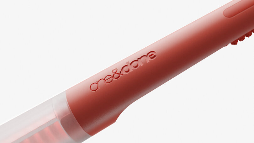 Detail of one&done logo across the toothbrush head holder in coral finish.