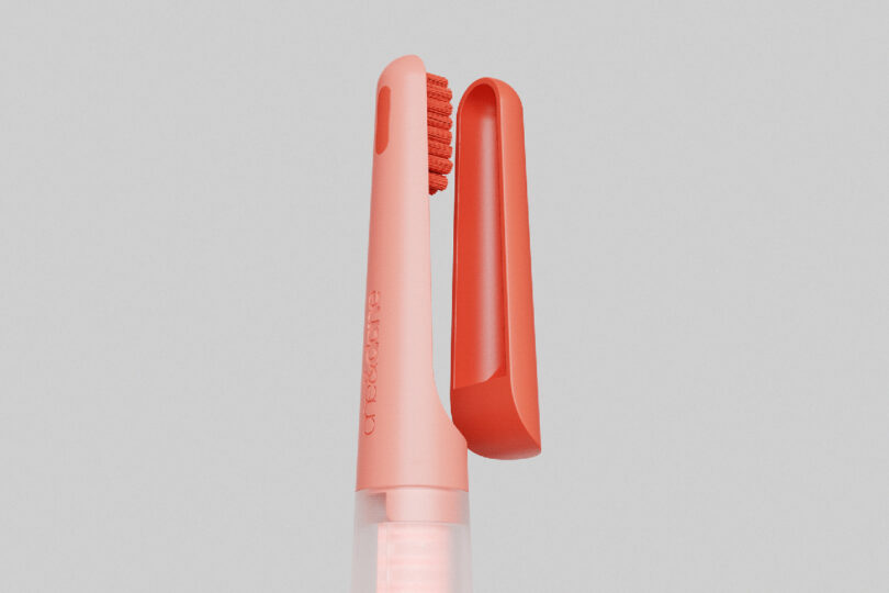 Detail of the coral red toothbrush with its magnetic plastic brush cover.