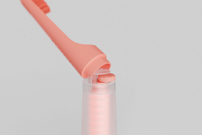 Close up the toothbrush tablet dispenser section of the one&done toothbrush in coral finish.