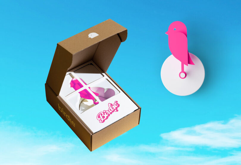 Variante da edição especial rosa da Barbie do monitor de qualidade do ar Birdie, mostrada em sua caixa e também como um recorte contra o fundo do céu azul