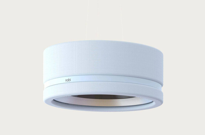 Nobi ceiling lamp in white cloth shade with branded band, set against cream background.