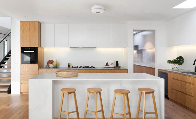 Nobi ceiling lights installed over a contemporary kitchen island with four wooden stools in the foreground.