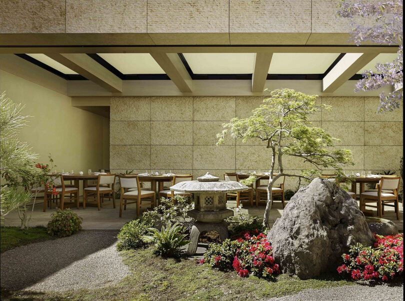 Nobu Hotel restaurant's Japanese rock garden landscaped with California native plants and outdoor dining furniture, with stone pagoda statue and large landscape rock in foreground with maple planted in between.