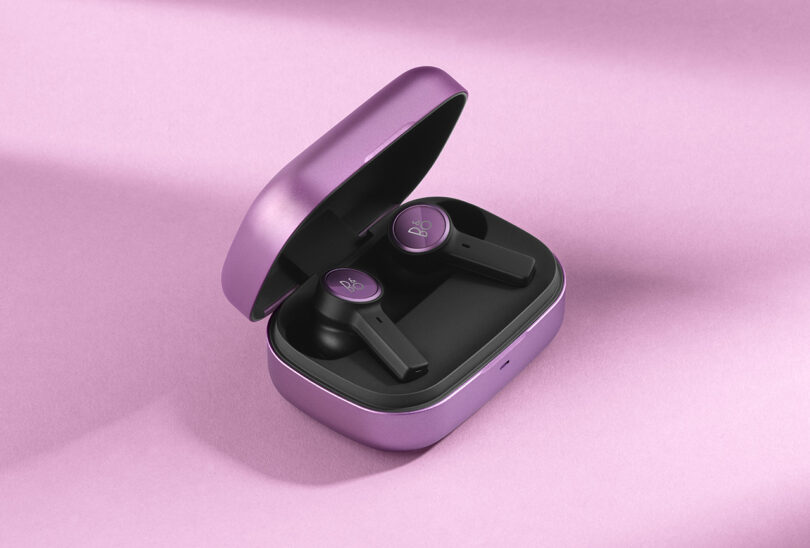 Beoplay EX Lilac Purple with case open revealing two black earbuds with lilac detailing and B&O logo.