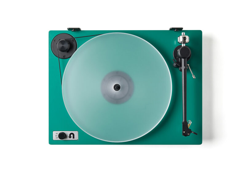 Green Orbit Special turntable with clear acrylic platter with Red Ortofon needle without dust cover, staged against white background and viewed from overhead showing its seamless belt drive in the upper left corner and speed dial control in the lower left.