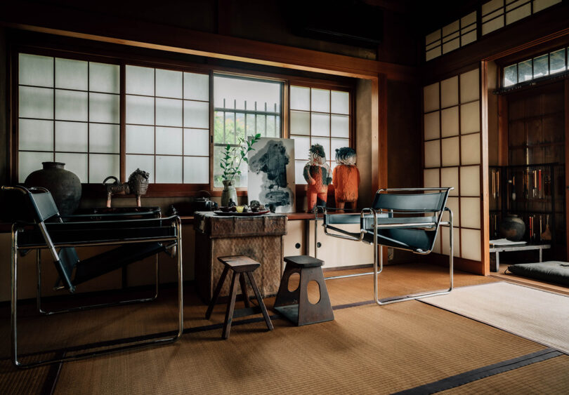 Wassily armchairs and small side stools set across tatami flooring with sliding rice paper partitions and windows nearby, with numerous contemporary and traditional ceramic pieces decorating a nearby storage shelf.