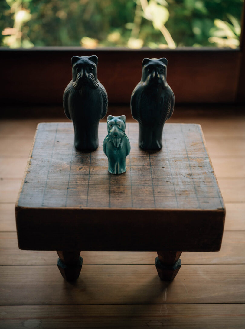 Three modern zoomorphic ceramic sculptures set across small antique Go boardgames playing table. 
