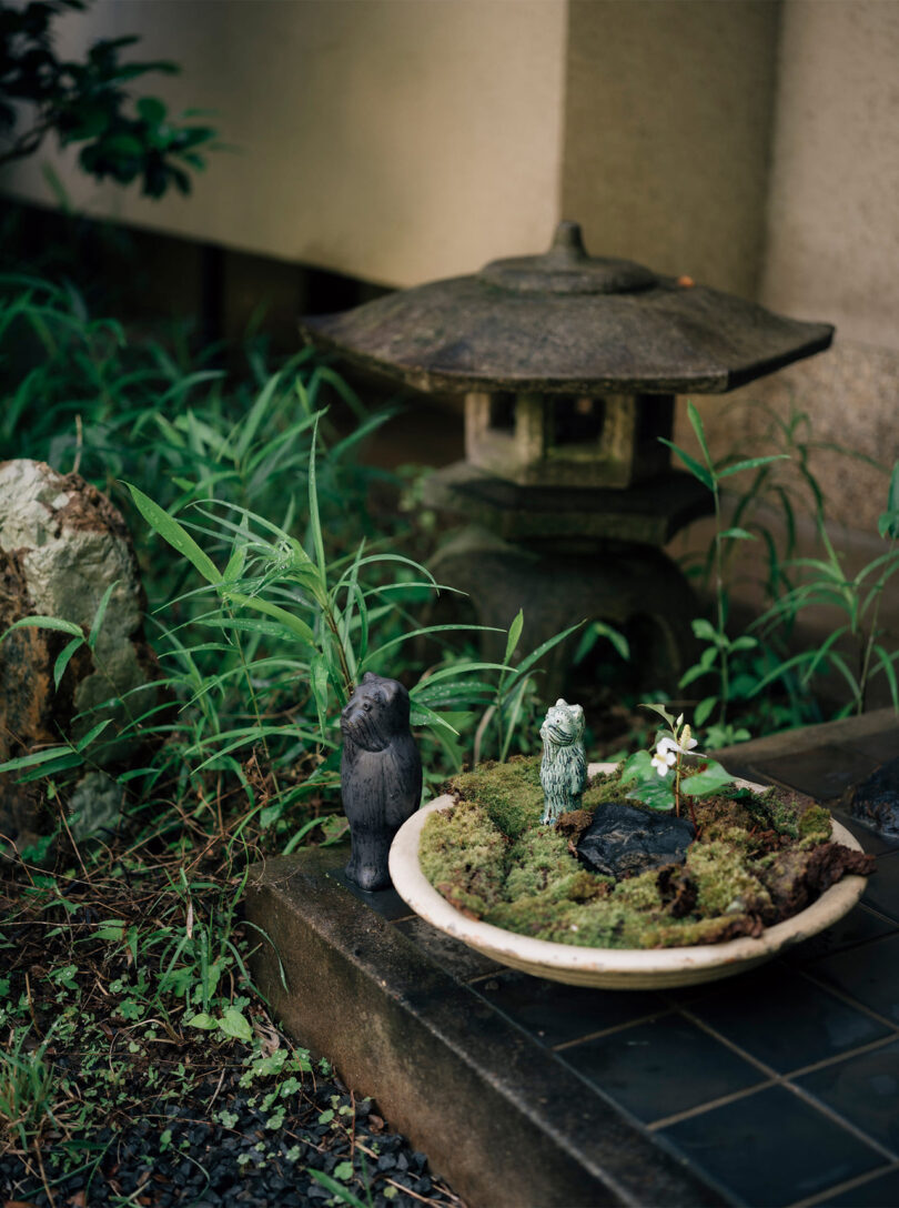 Corner detail shot of the home's small tea garden called "roji", decorated with Japanese ritual stones and Ukrainian DIDO art sculptures from the MAKHNO workshop situated near a moss-filled ceramic bowl.