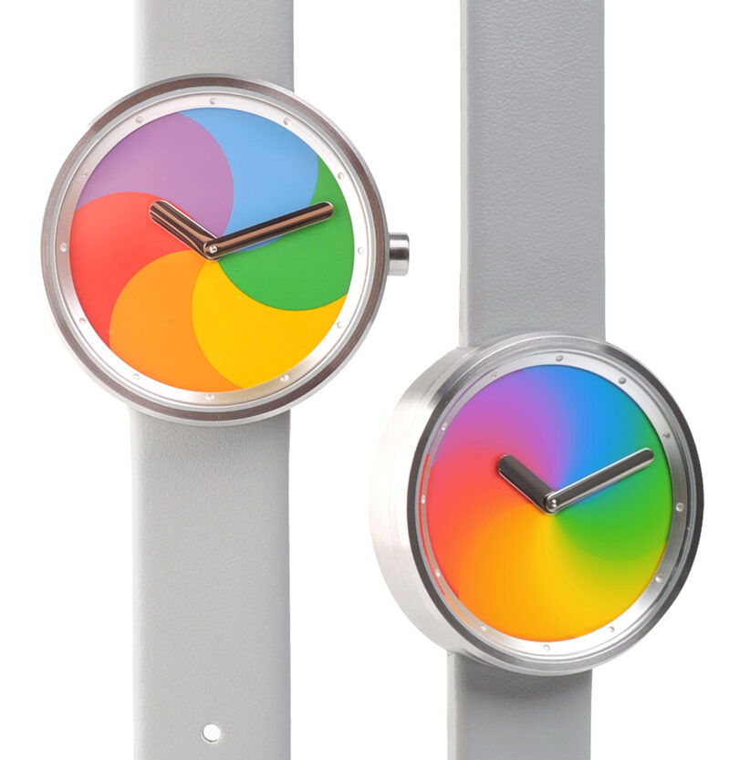 Side by side The Trio of Time The Spinning Beach Ball wrist watch, one on the left static, with another watch with kinetic color wheel in blurred motion.