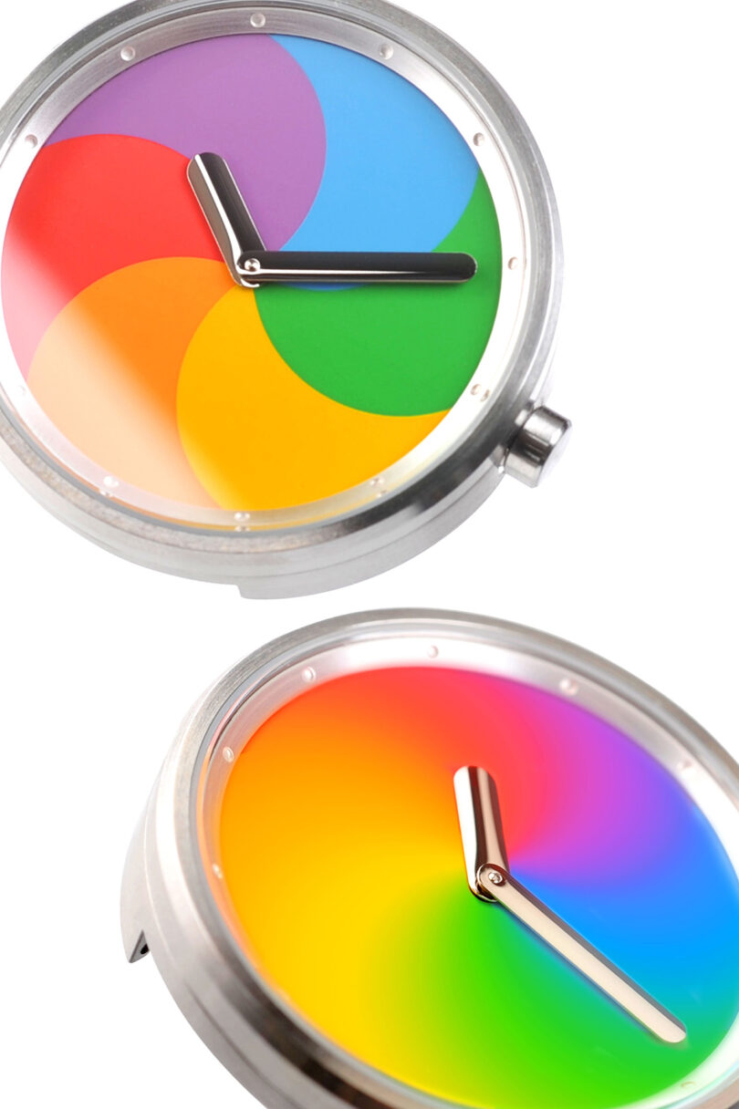 Close-up of two side by side The Trio of Time The Spinning Beach Ball wristwatches, one on the top in static position, with another watch below it in blurred motion.