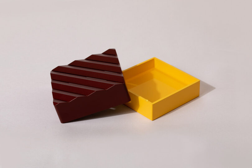 One square shaped ridged red-brown and second yellow Conecto tray staged next to one another.