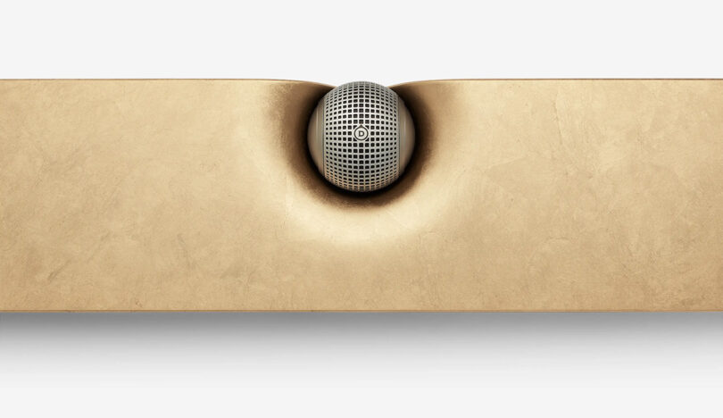 Top cropped view of special edition Devialet Dione Opéra de Paris soundbar, with spherical center speaker in the front center and gold leaf covered top.