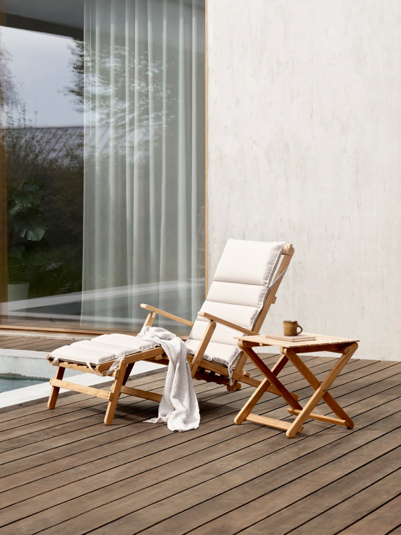 outdoor wood chaise lounge with white cushions and matching side table