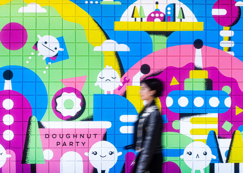 pink, blue, green, and yellow wall mural with a person walking in front of it