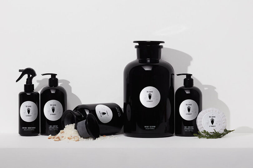 five black apothecary bottles with white labels styled on all white surfaces