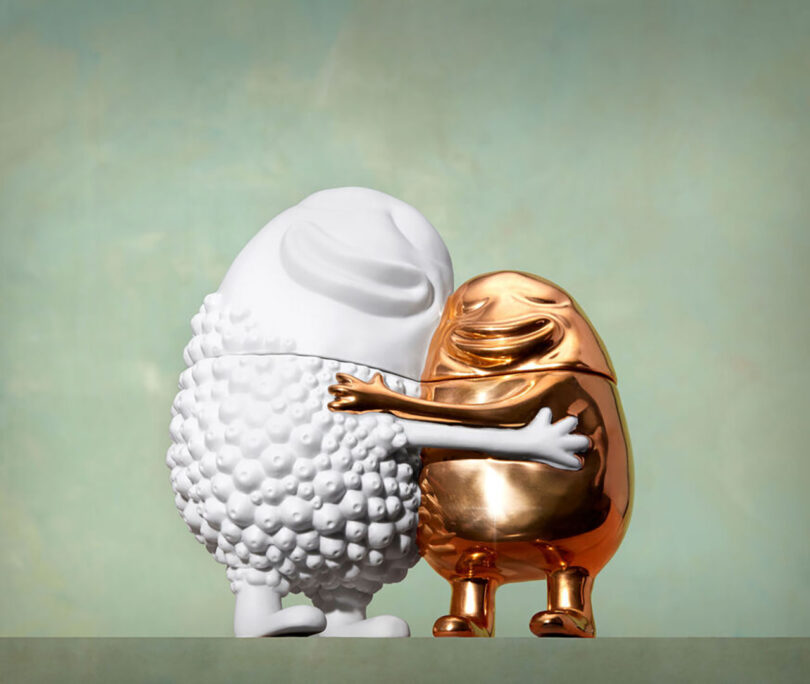 one white and one gold squat bulbous character embrace each other