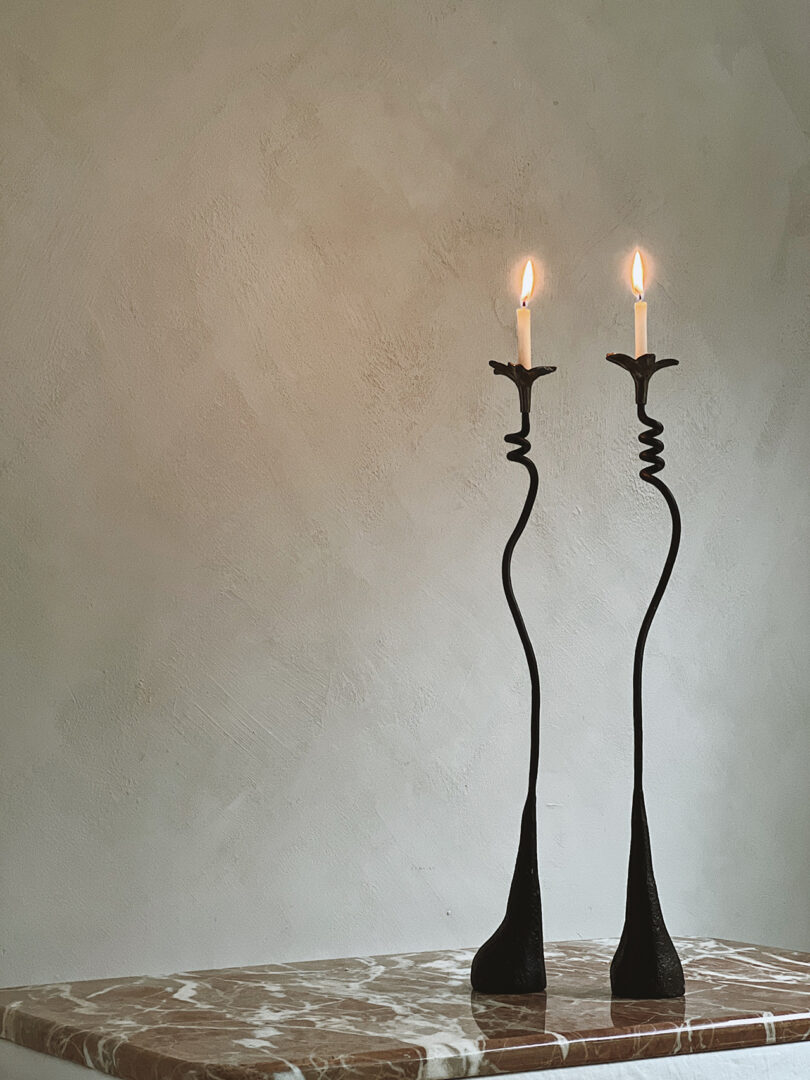 two curvaceous black candlestick holders with lit candles