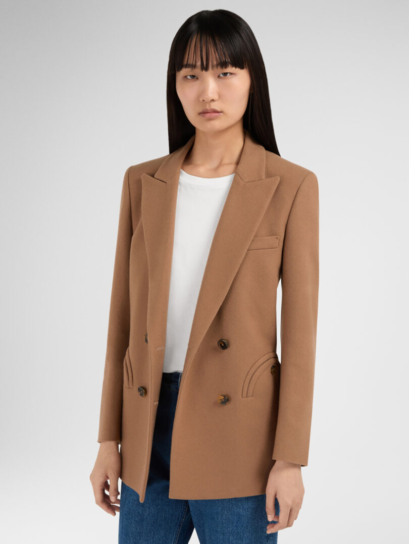 woman with long dark hair models a camel colored blazer