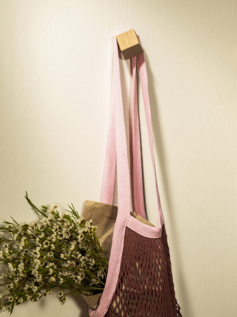 cube-shaped wall hook with a reusable bag filled with greens hanging from it
