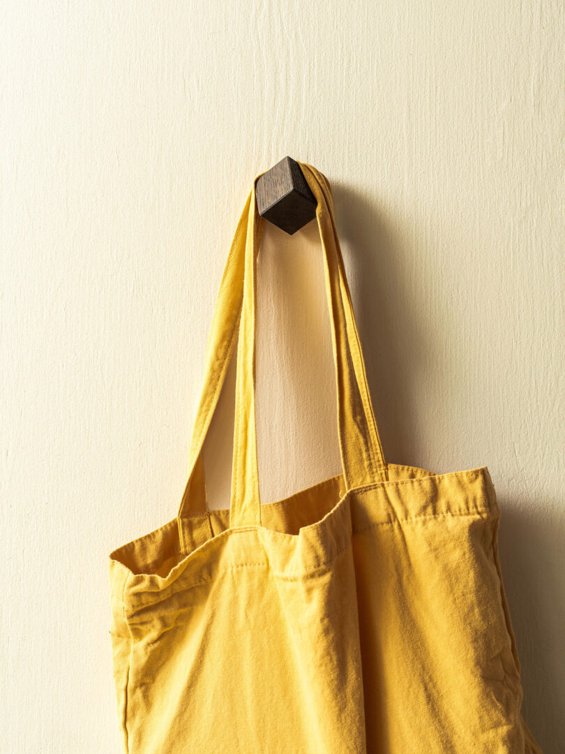 cube-shaped wall hook with a yellow tote hanging from it