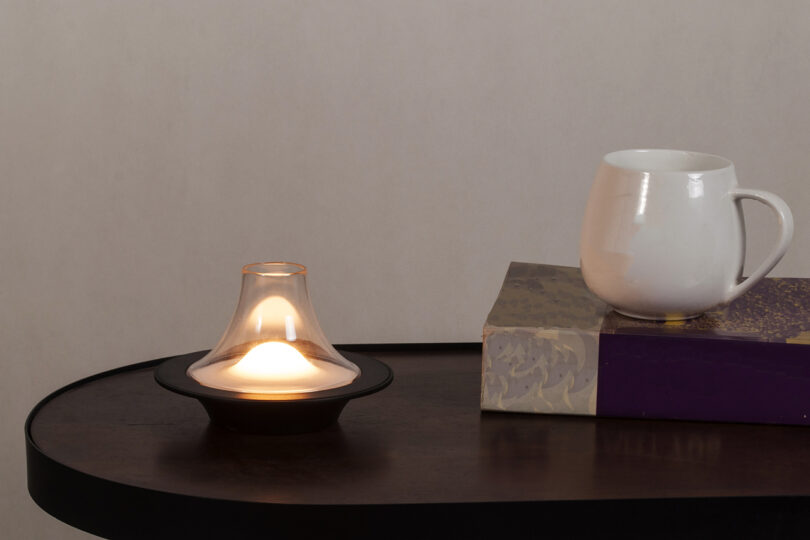 mushroom shaped glass table lamps sits on a surface with a mug