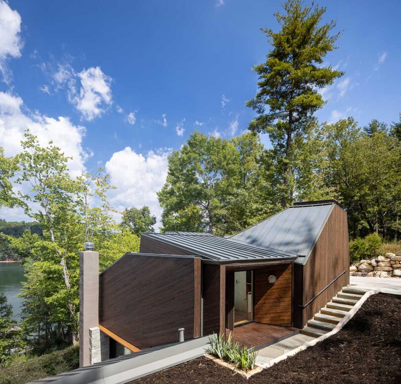down exterior view of modern brown house on hill with trees behind